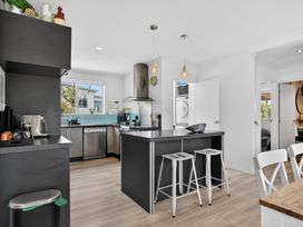 A kitchen with an island and bar stools at Little Pearl of Vista Verano - Mangawhai Village
