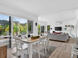 A living room with a sofa, dining area, and sliding doors at Little Pearl of Vista Verano - Mangawhai Village