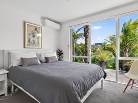 A bedroom with a bed and large windows at Little Pearl of Vista Verano - Mangawhai Home in Mangawhai Village