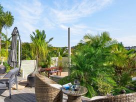 A garden area with patio furniture and palm trees at Little Pearl of Vista Verano - Mangawhai Village