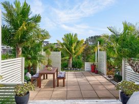 A garden with palm trees and a table with chairs at Little Pearl of Vista Verano - Mangawhai Village