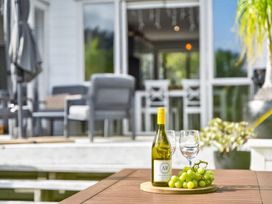 A wine bottle and glass with grapes on a table at Little Pearl of Vista Verano - Mangawhai Village