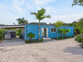 A house with a carport and palm trees at Little Pearl of Vista Verano - Mangawhai Village