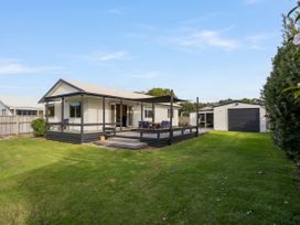 A house with a deck and chairs at Nest by the Beach - Cooks Beach
