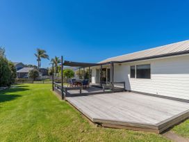 A garden with a deck and outdoor furniture at Nest by the Beach - Cooks Beach