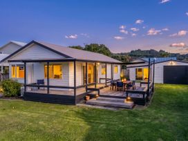A house with a deck and outdoor furniture at Nest by the Beach - Cooks Beach