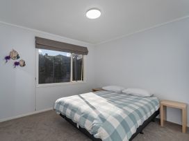 A bedroom with a bed and a window at Nest by the Beach - Cooks Beach