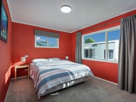 A bedroom with a bed and nightstand at Nest by the Beach - Cooks Beach