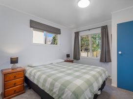 A bedroom with a bed and two nightstands at Nest by the Beach - Cooks Beach