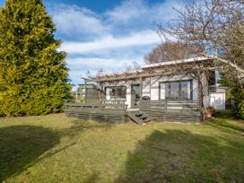 A house with a deck and outdoor seating at Wharewaka Bach - Lake Taupo Holiday Home in Wharewaka