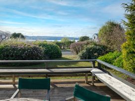 An outdoor area with a deck and bushes at Wharewaka Bach - Lake Taupo Holiday Home, Wharewaka