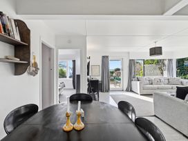 A dining table with chairs and a view of a living room at Wharewaka Bach - Lake Taupo Holiday Home Wharewaka