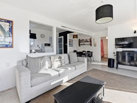 A living room with a sofa and television at Wharewaka Bach - Lake Taupo Holiday Home in Wharewaka