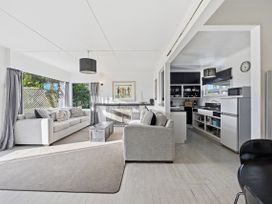 A living room with a sofa and kitchen area at Wharewaka Bach - Lake Taupo Holiday Home in Wharewaka