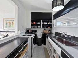 A kitchen with appliances and storage at Wharewaka Bach - Lake Taupo Holiday Home in Wharewaka