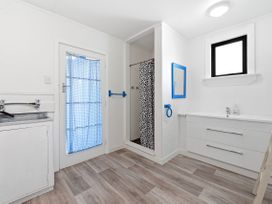 A bathroom with a sink, shower, and drawer unit at Wharewaka Bach - Lake Taupo Holiday Home, Wharewaka
