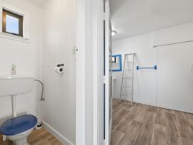 A bathroom with a toilet and a window at Wharewaka Bach - Lake Taupo Holiday Home in Wharewaka