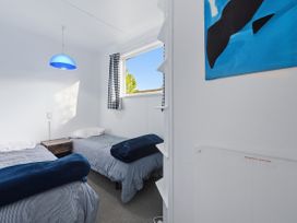 A bedroom with two beds and a lamp at Wharewaka Bach - Lake Taupo Holiday Home, Wharewaka