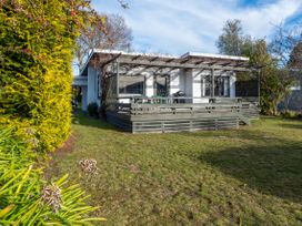 A house with a deck and lawn at Wharewaka Bach - Lake Taupo Holiday Home, Wharewaka