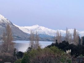 A view of mountains and a lake with trees in the foreground at Lakeside Escape - Wanaka Holiday Bach Wanaka