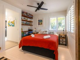 A bedroom with a bed and bookshelves at Moa Magic - Oneroa Holiday Home Oneroa