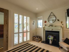 A living room with a fireplace and windows at Moa Magic - Oneroa Holiday Home, Oneroa