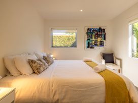 A bedroom with a bed and artwork on the wall at Moa Magic - Oneroa Holiday Home Oneroa