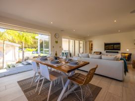 A living room with a dining area and outdoor view at Moa Magic - Oneroa Holiday Home Oneroa