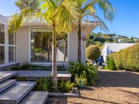 An outdoor view of a house with a palm tree and pathway at Moa Magic - Oneroa Holiday Home Oneroa