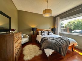 A bedroom with a bed, dresser, and window at Stag & 3 Pigs - Ohakune