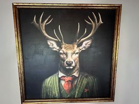A deer wearing a suit with antlers in a framed portrait at Stag & 3 Pigs - Ohakune