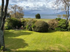 A garden with chairs and bushes overlooking a lake at Kuratau Classic - Kuratau Holiday Home