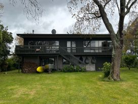 A house with a deck and stairs in front at Kuratau Classic - Kuratau Holiday Home Kuratau