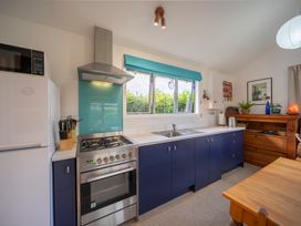 A kitchen with stove, sink, and refrigerator at Beech Retreat - Te Anau Holiday Home