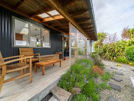 Outdoor area with wooden furniture and plants at Beech Retreat - Te Anau Holiday Home