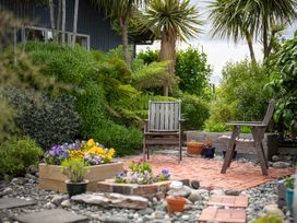A garden with chairs and flower planters at Beech Retreat - Te Anau Holiday Home, Te Anau
