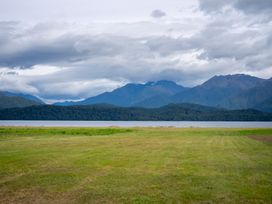 A landscape view with grass, water, and mountains at Beech Retreat - Te Anau Holiday Home Te Anau