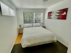 A bedroom with a bed and nightstand at Gone Coastal - Whangamata Holiday House in Whangamata