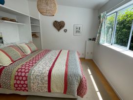 A bedroom with a bed and window at Gone Coastal - Whangamata Holiday House, Whangamata