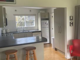 A kitchen with a sink, refrigerator, and dishwasher at Gone Coastal - Whangamata Holiday House in Whangamata