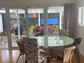 A dining room with a glass table and chairs at Gone Coastal - Whangamata Holiday House in Whangamata