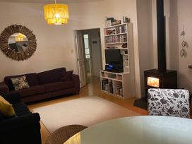 A living room with a sofa, television, and stove at Gone Coastal - Whangamata Holiday House in Whangamata