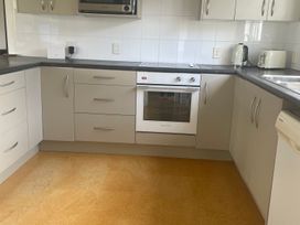 A kitchen with cabinets, an oven, a kettle, and a toaster at Gone Coastal - Whangamata Holiday House, Whangamata