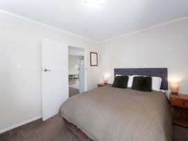 A bedroom with a bed and nightstand at Camellia with WiFi - Paihia