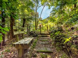A path with a bench and steps in a forested area at Camellia with WiFi - Paihia