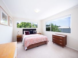 A bedroom with a bed and windows at Rimu - Paihia Holiday Home in Paihia