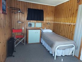 A bedroom with a bed, chair and cabinet at Kenshaw Cottage - Omori Bach in Omori