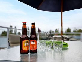 Two beer bottles and glasses on a table in the outdoor seating area at Kinloch Family Retreat - Kinloch Holiday Home, Acacia Bay
