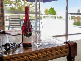 A wine bottle and glass on a table at Kinloch Family Retreat - Kinloch Holiday Home Acacia Bay