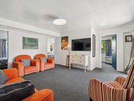 A living room with orange sofas and a television at Riverbed Lodge - Lake Taupo Home Tauranga Taupo